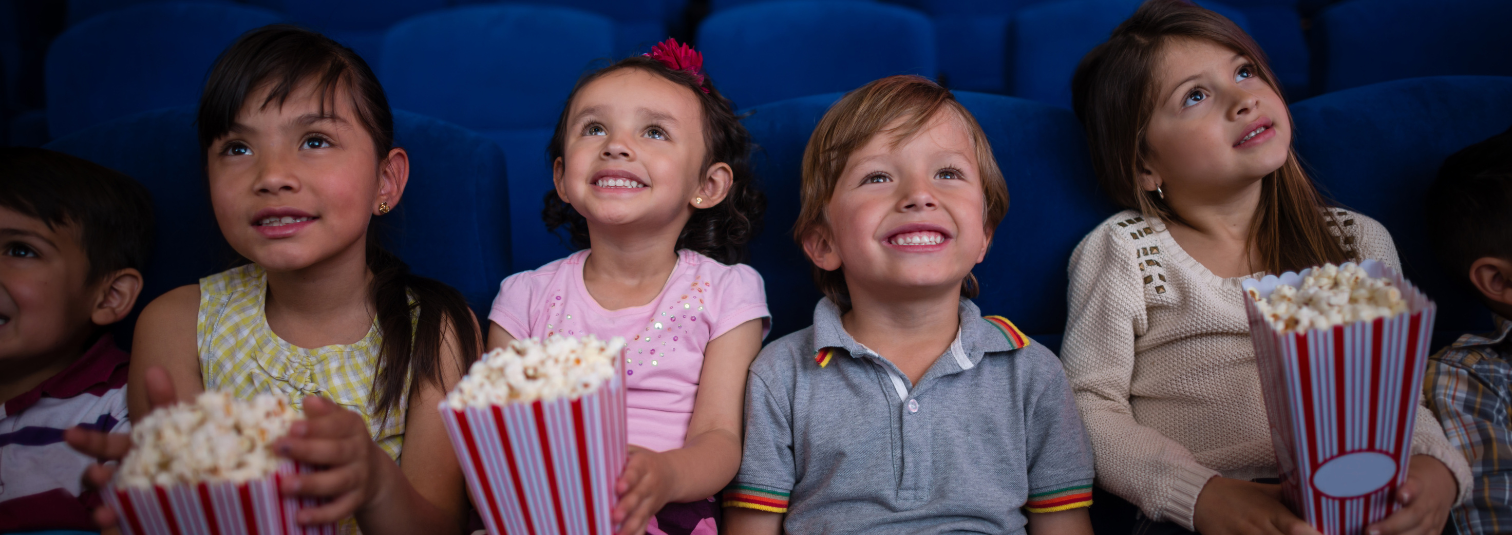 Young children eating popcorn in cinema