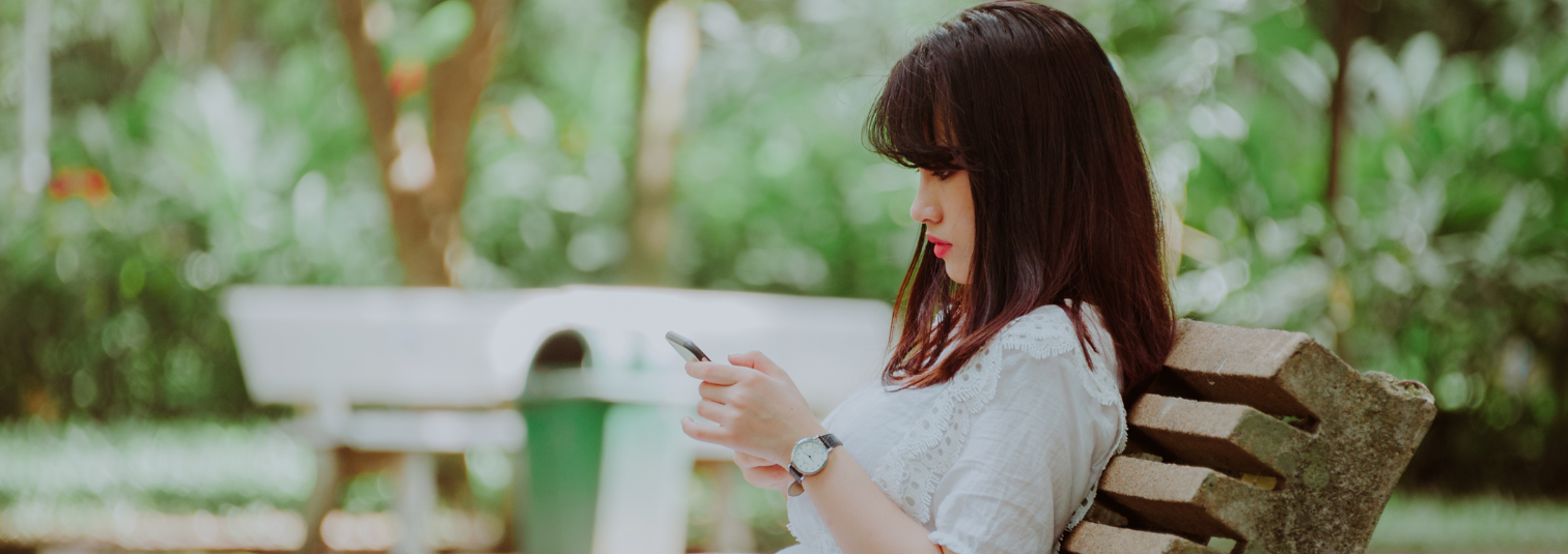 Young woman in a garden reading something on her phone